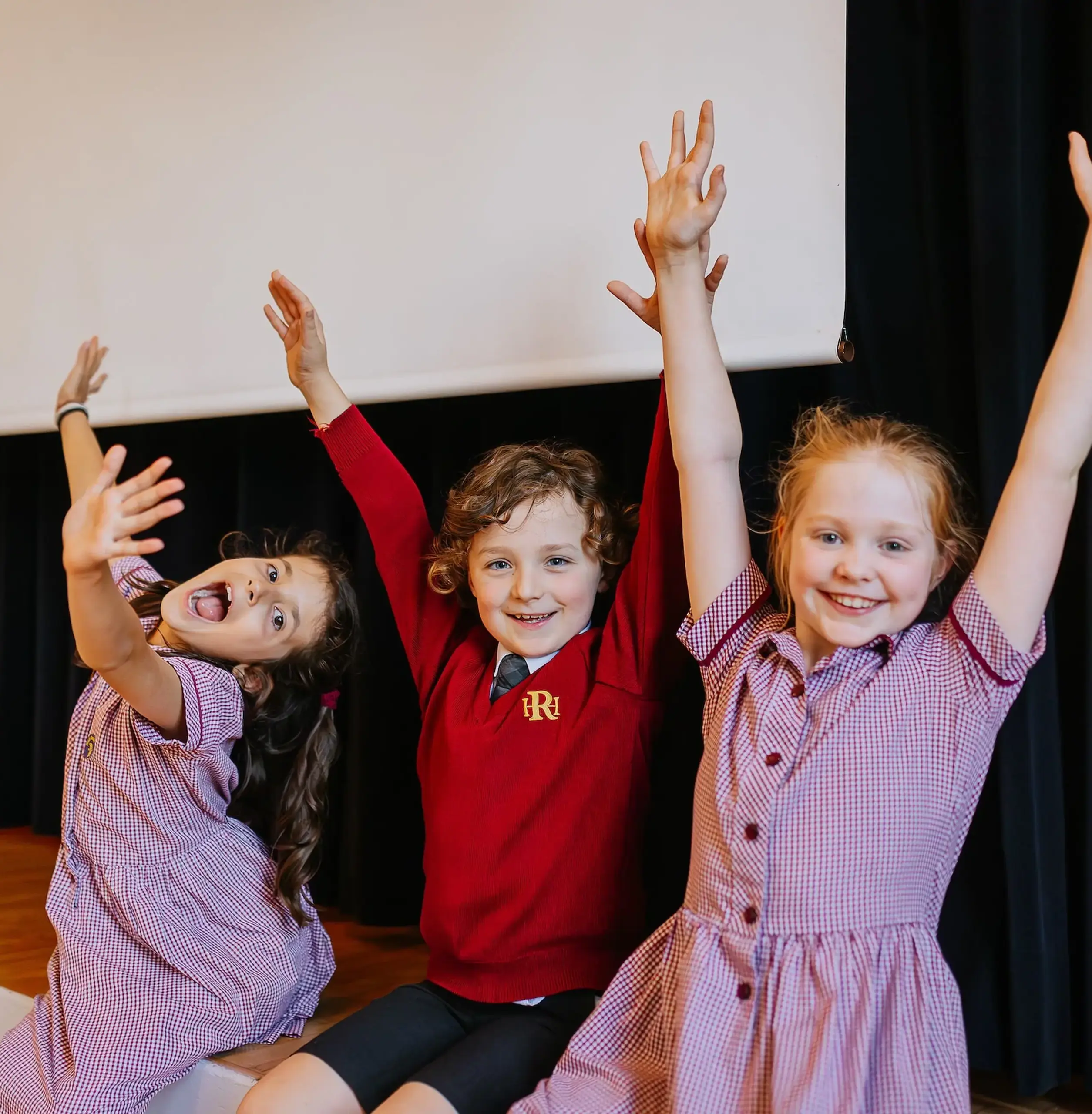 Three children throwing their arms up in celebration