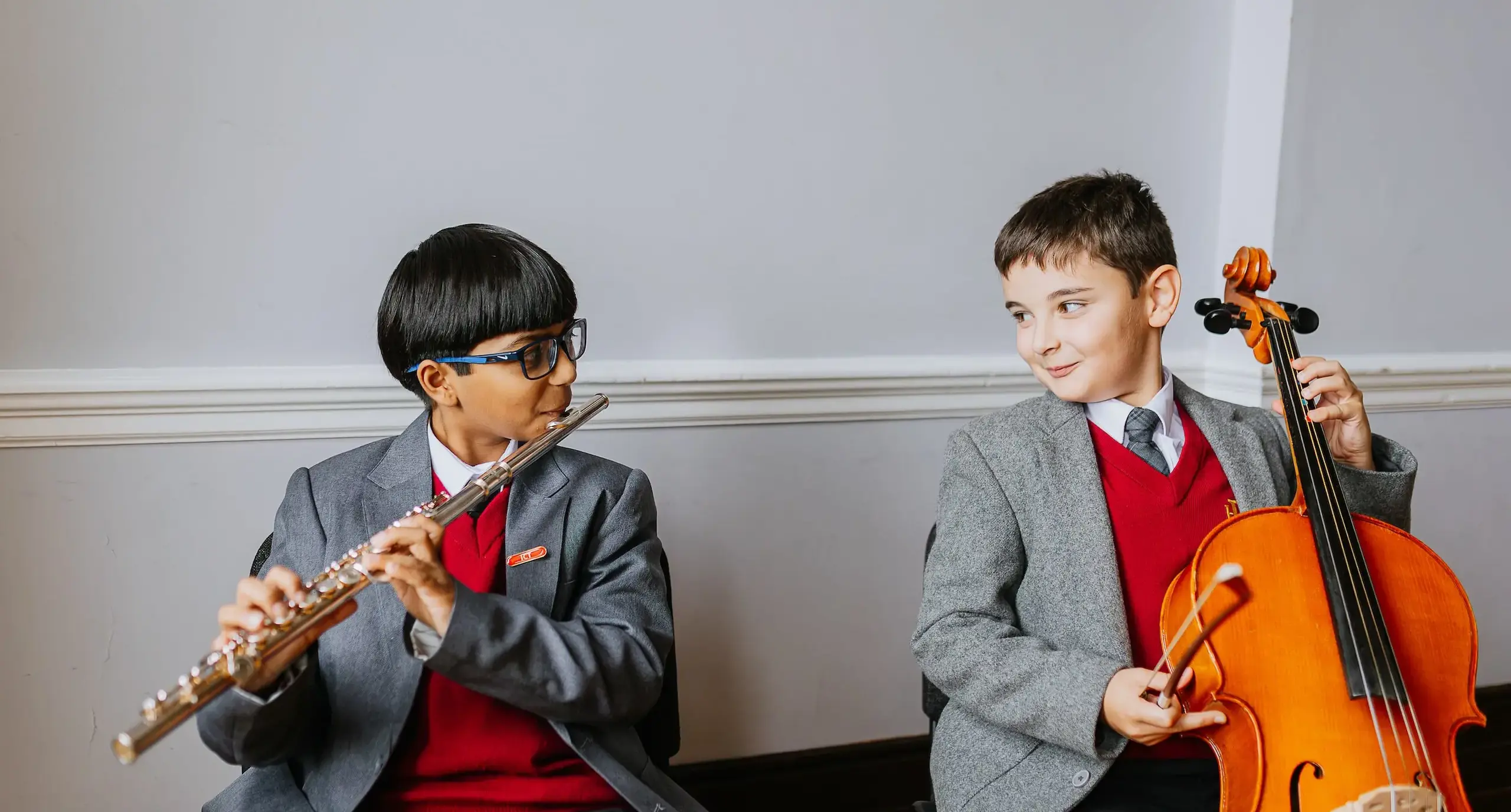 Two student musicians, one holding a flute and the other a cello