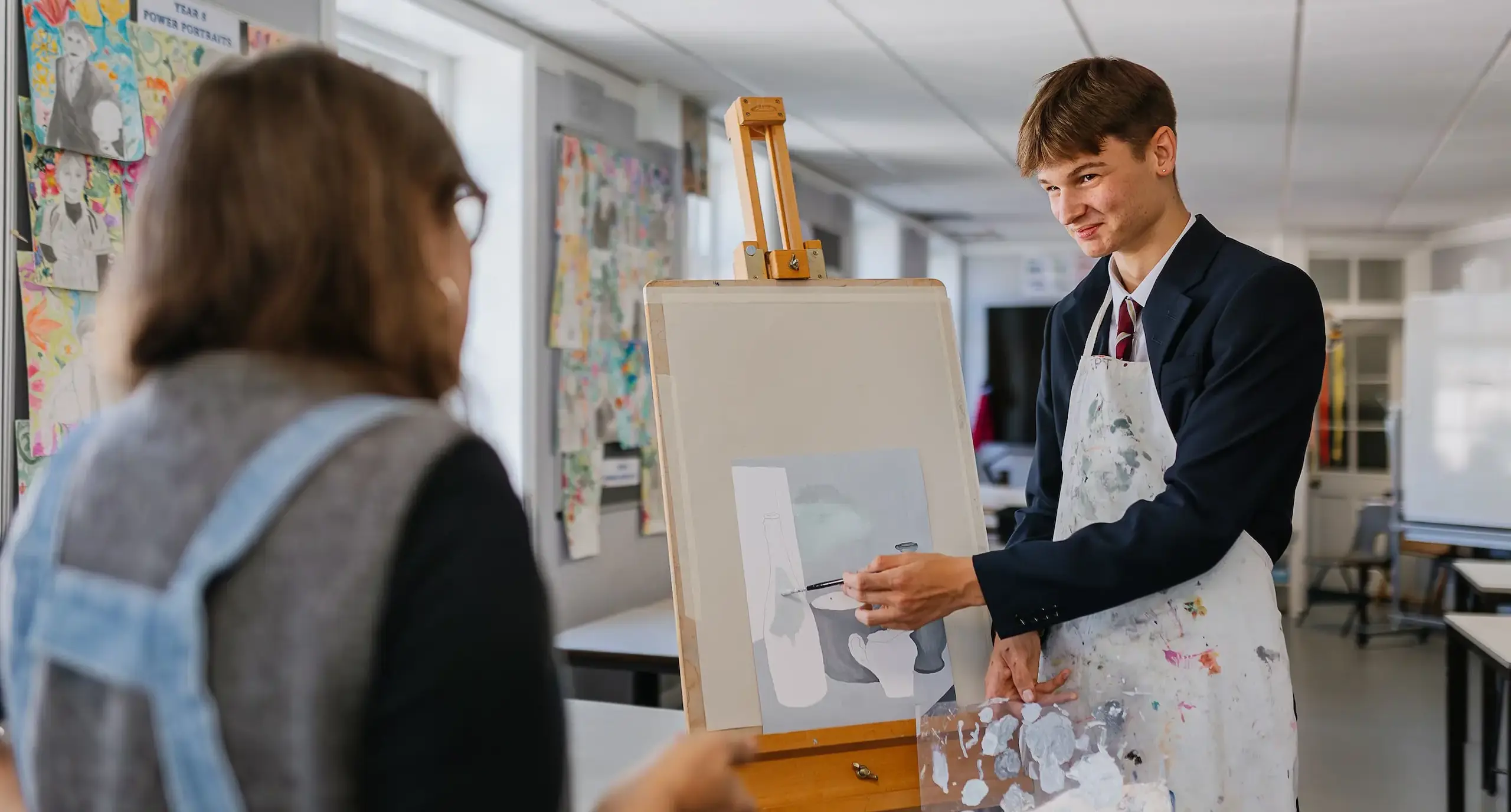 Radnor student painting on an easel under guidance form teacher