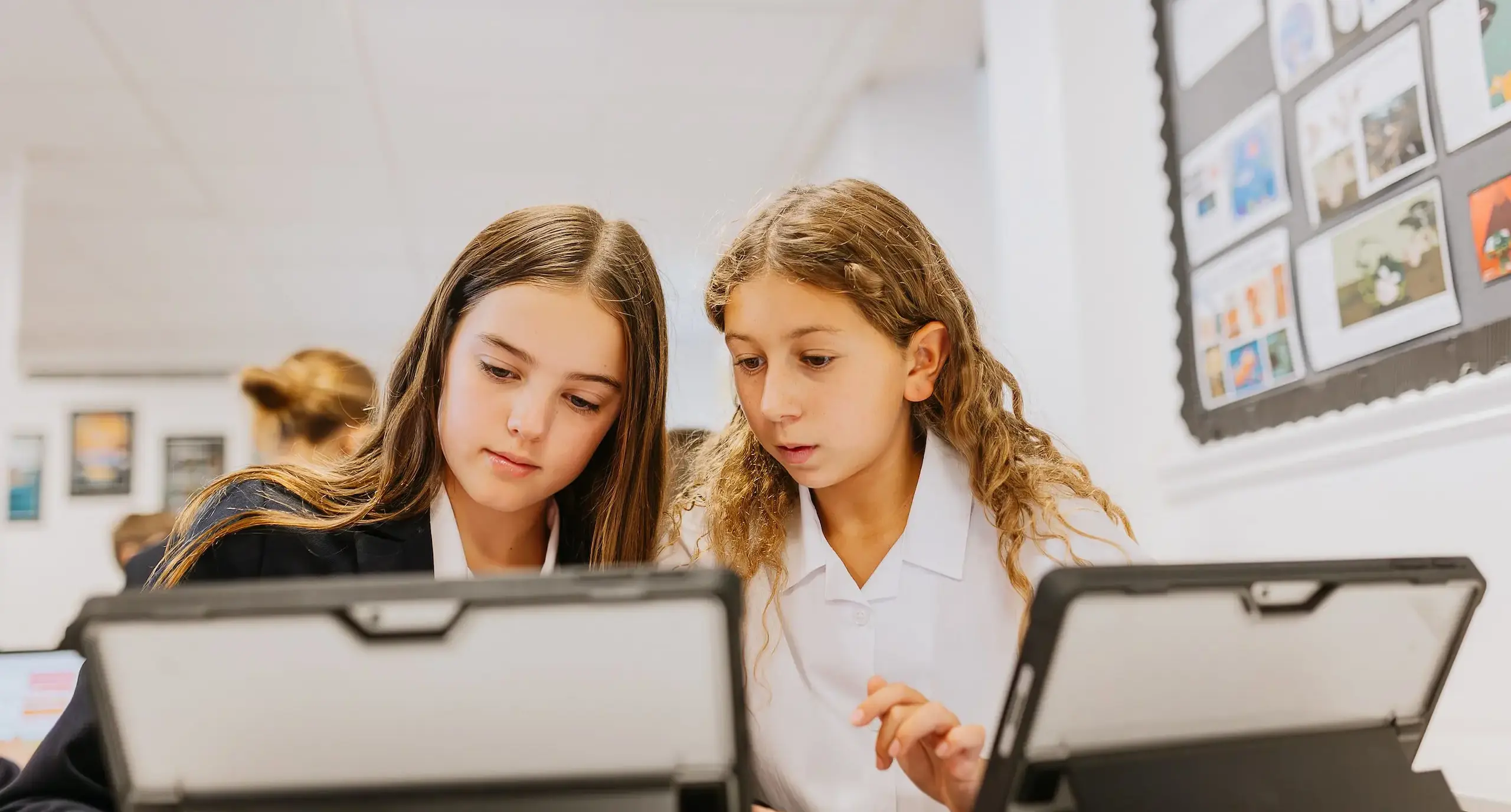 Two students looking at an iPad, heads together