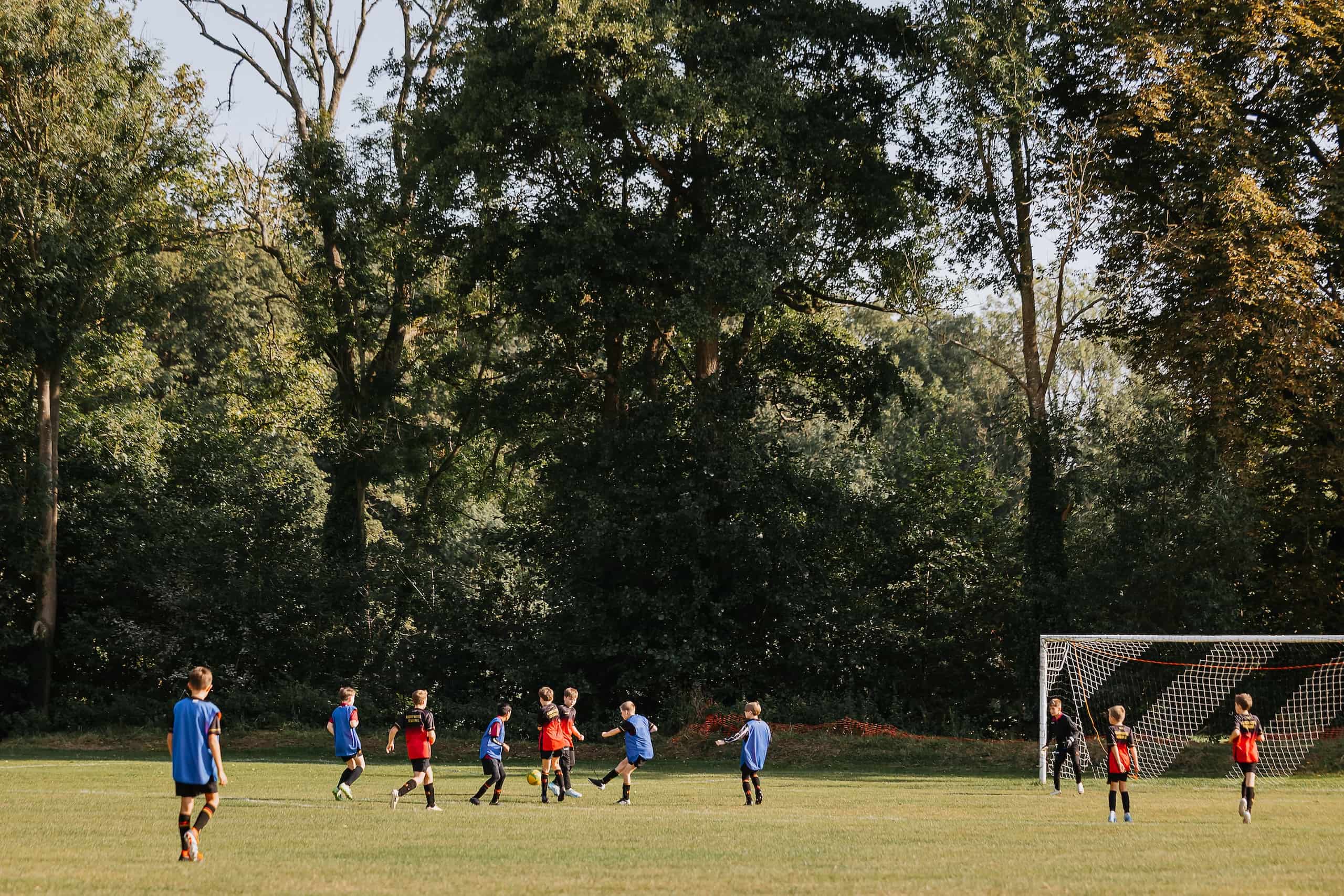 Rdnor students playing football against a backdrop of trees