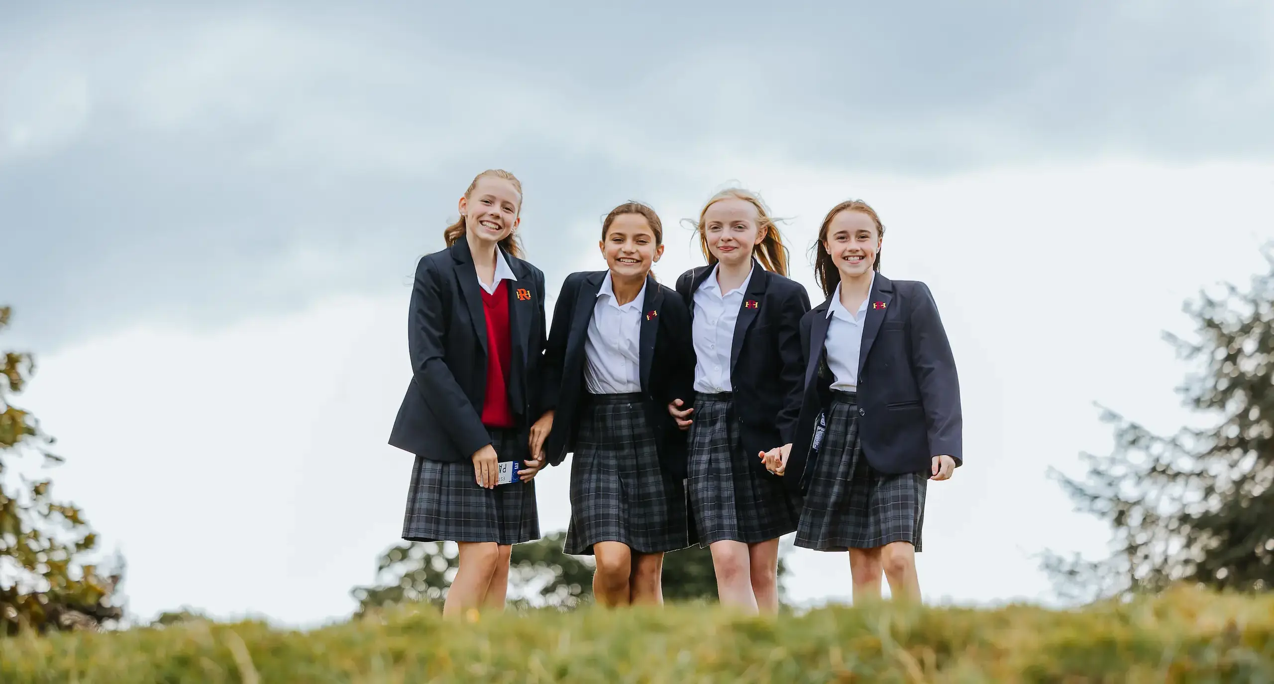 Four girls standing at the top of a small hill